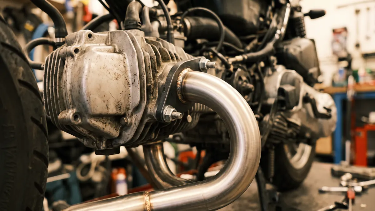 Colector de escape de acero inoxidable atornillado a la culata de un scooter