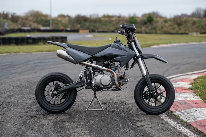 Pit bike de supermotard con el escape subiendo por el lateral y el silencioso bajo el asiento